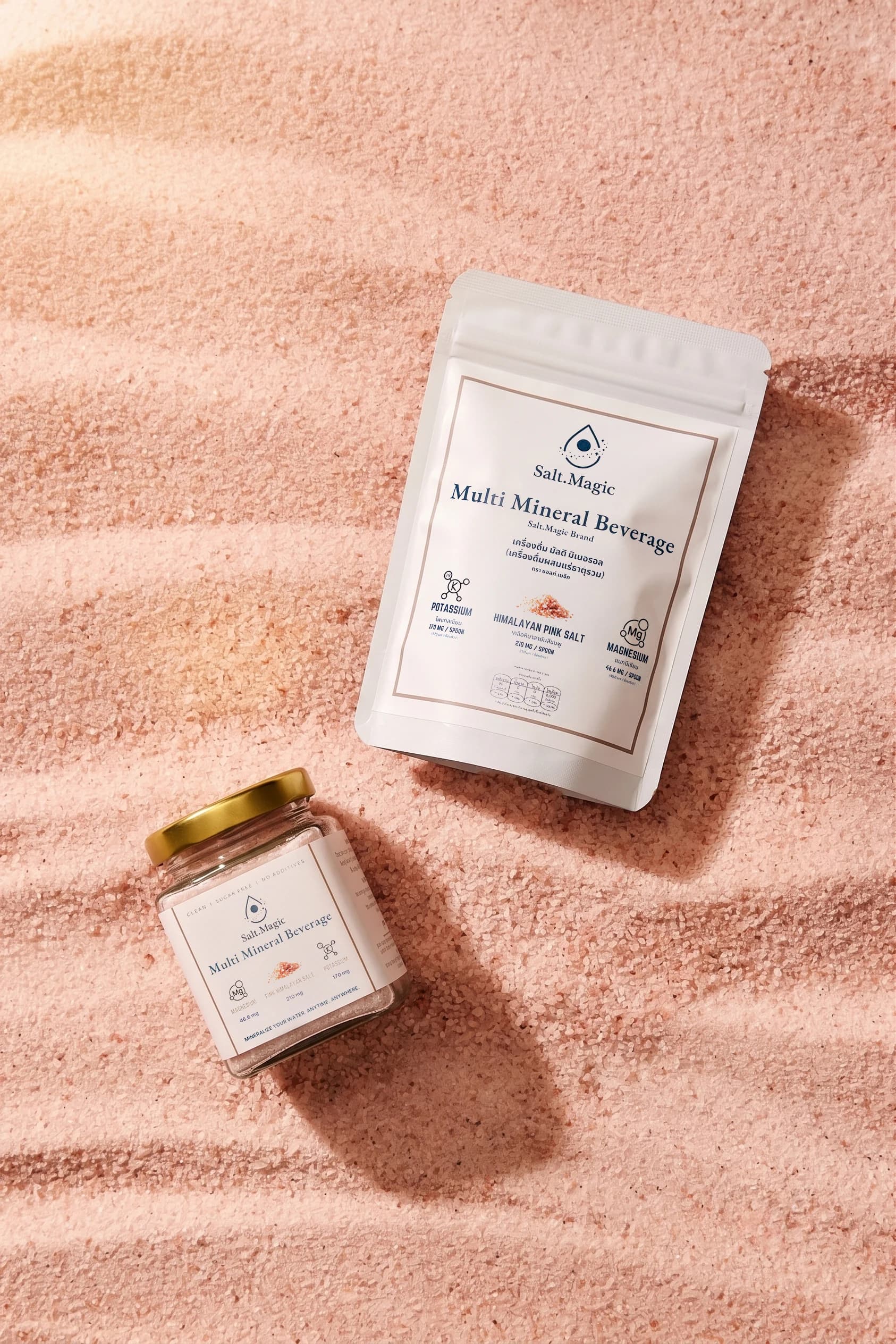 Salt.Magic electrolytes sachet and jar sitting in a bed of pink himalayan sea salt